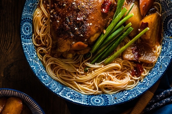 These spicy chicken noodles feature a super rich broth with juicy chicken. Learn to use the steam braising skill to cook a very flavorful chicken in much less time! | omnivorescookbook.com