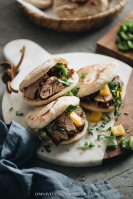 Three pork belly buns on marble serving board