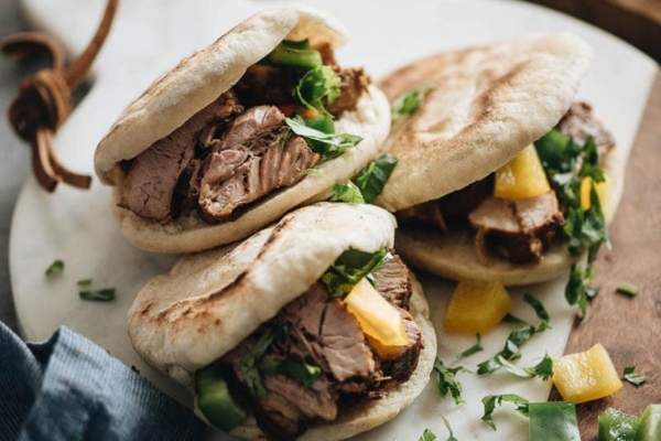 Three pork belly buns on marble serving board