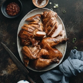 Sliced soy sauce chicken served with Sriracha, salt, and green onions