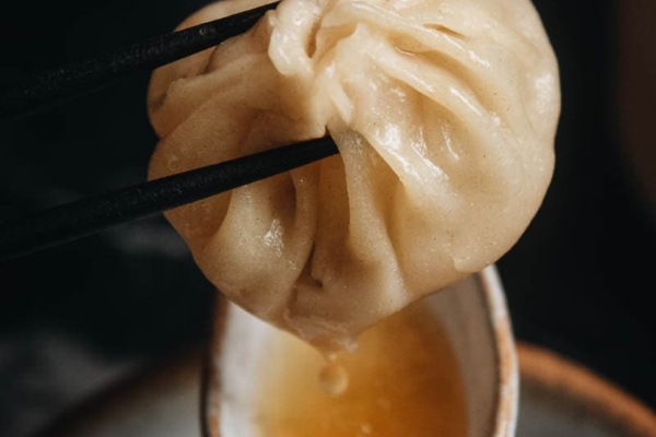 Homemade soup dumplings dripping soup into a spoon