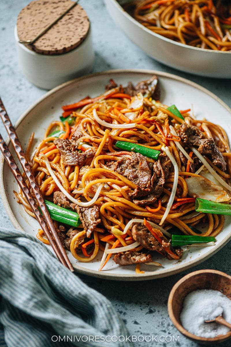 A plate of stir-fried Asian style noodles with chopsticks