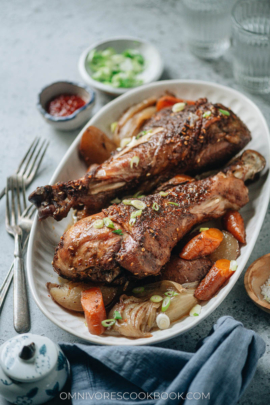 Roast turkey legs over a bed of vegetable served in a platter